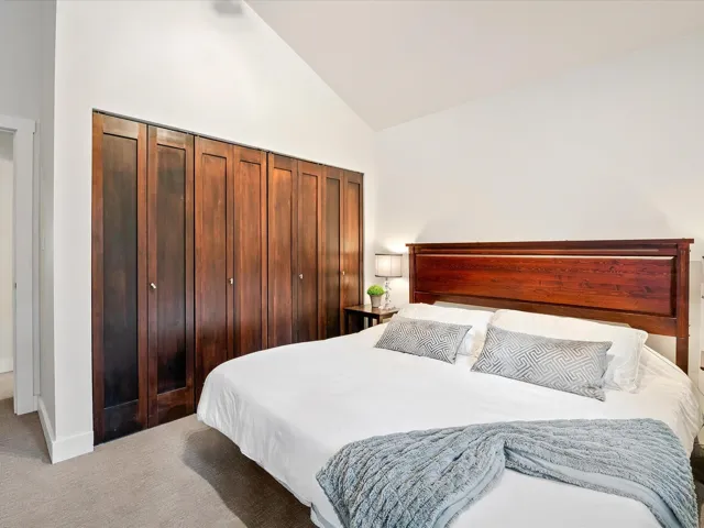 Carpeted bedroom featuring baseboards and high vaulted ceiling