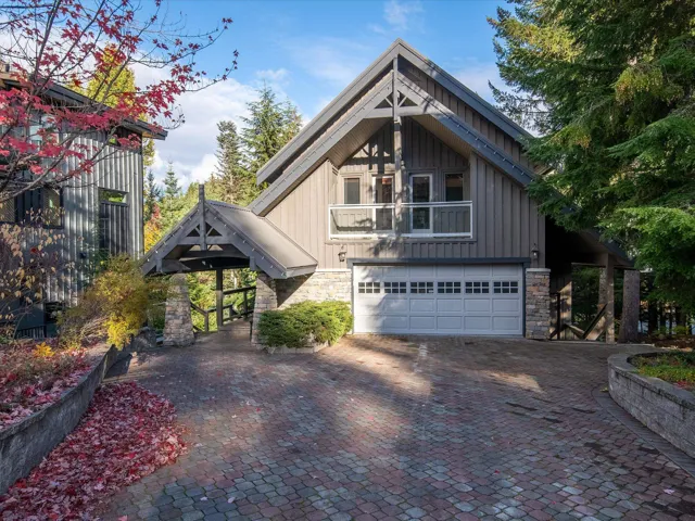 View of front of house featuring a garage, board and batten siding, decorative driveway, and stone siding