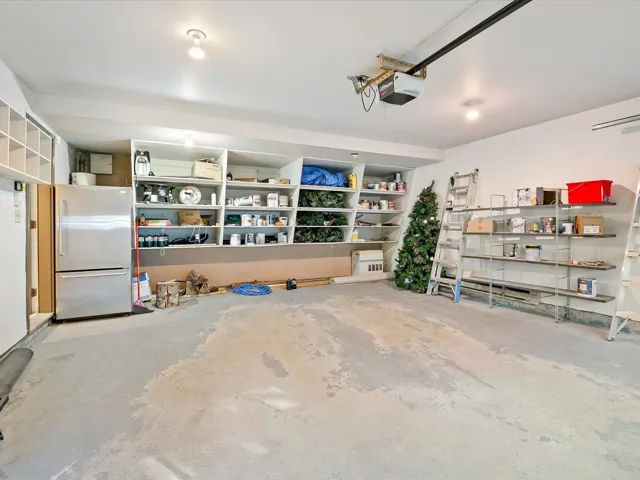 Garage with freestanding refrigerator and a garage door opener