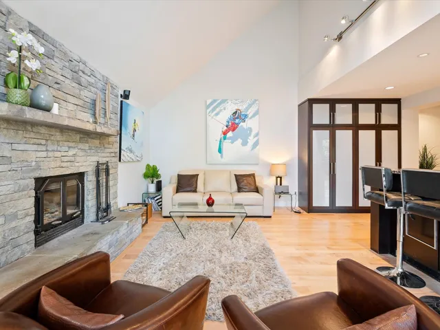 Living room with high vaulted ceiling, light wood-style flooring, and a fireplace
