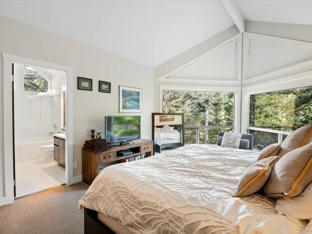 Carpeted bedroom with vaulted ceiling with beams and ensuite bathroom