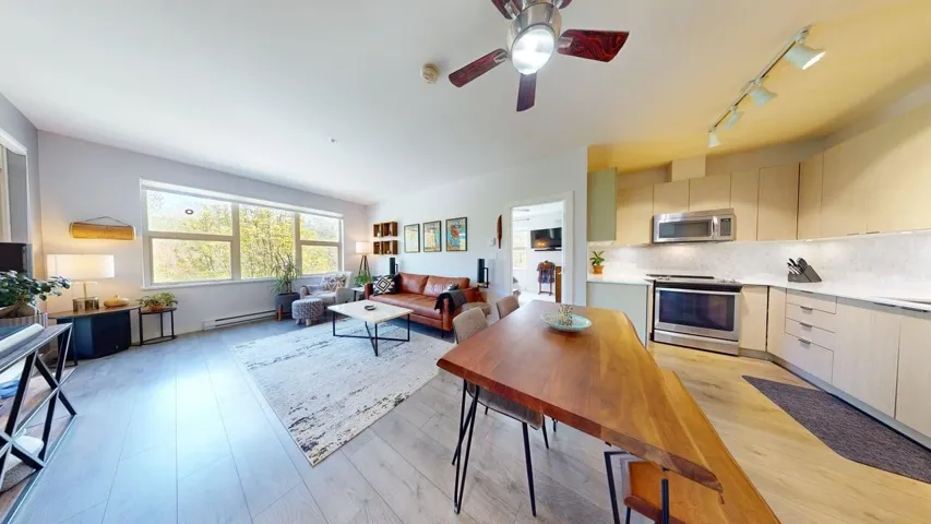 Kitchen featuring light wood-style flooring, stainless steel appliances, light countertops, , all in an open floor plan