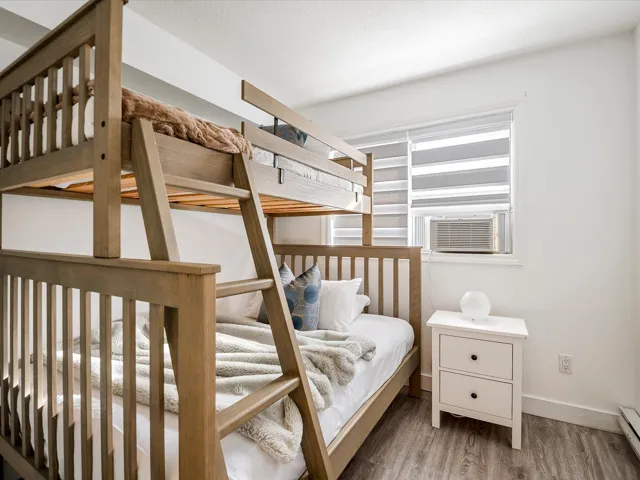 Bedroom featuring a baseboard radiator, cooling unit, baseboards, and wood finished floors