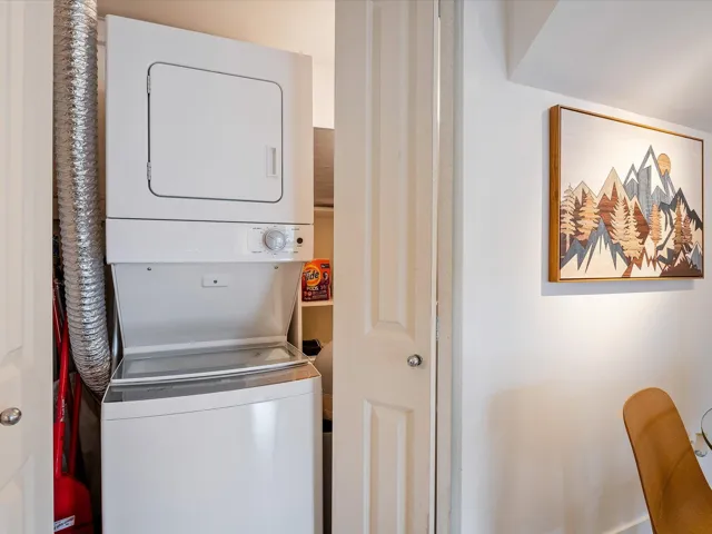 Clothes washing area featuring stacked washer and dryer and laundry area