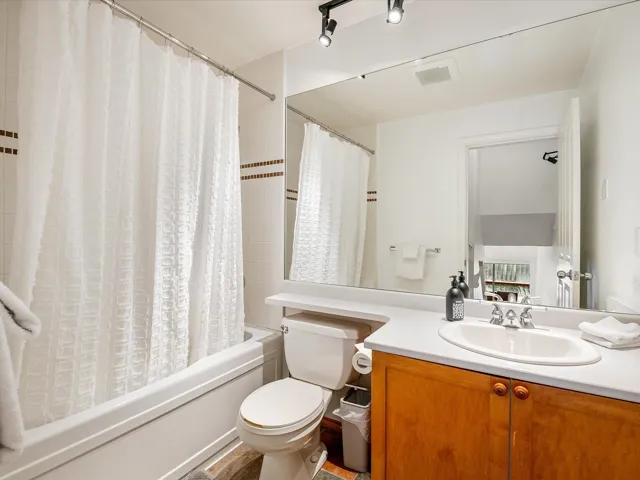 Full bath with visible vents, vanity, toilet, and shower / bathtub combination with curtain