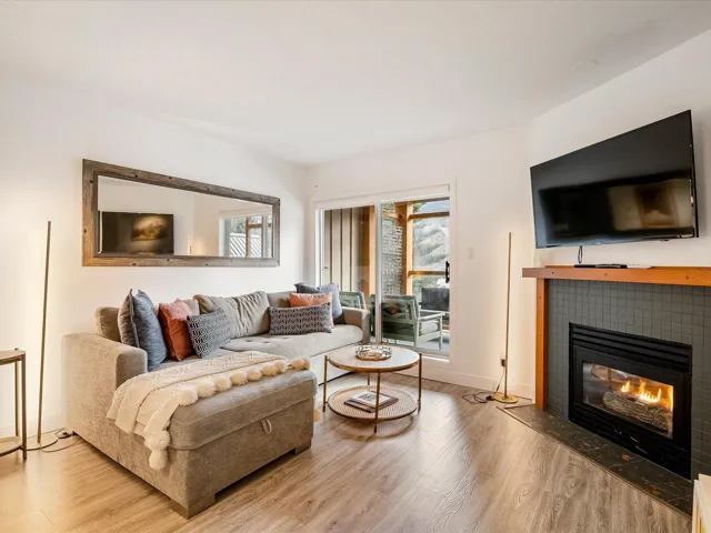 Living area with baseboards, a tiled fireplace, and wood finished floors