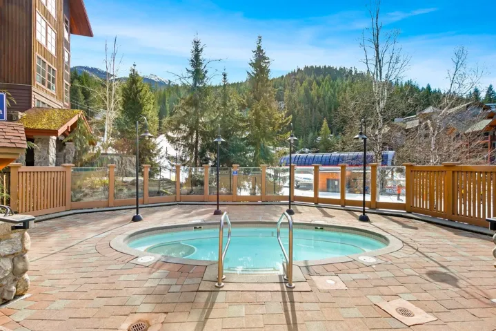View of pool with fence and a hot tub
