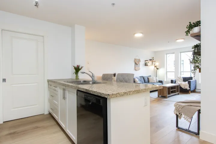 Kitchen featuring a sink, light wood finished floors, dishwasher, white cabinetry, and open floor plan