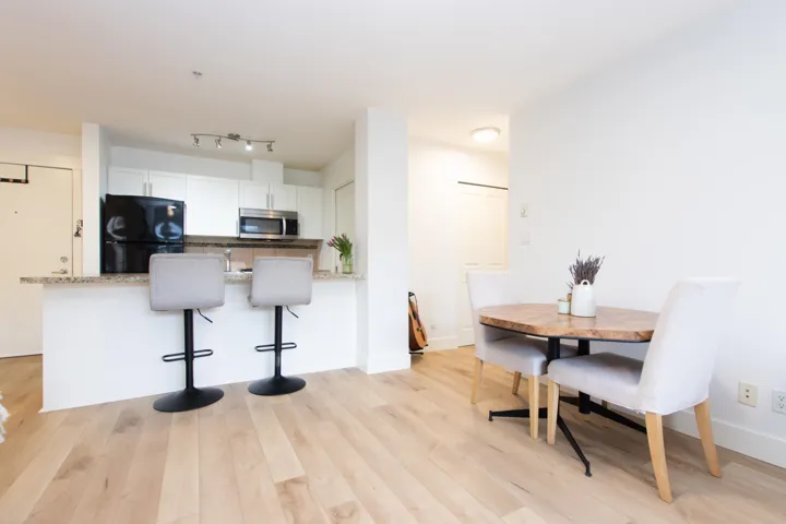 Kitchen featuring white cabinets, freestanding refrigerator, a peninsula, stainless steel microwave, and light wood-type flooring