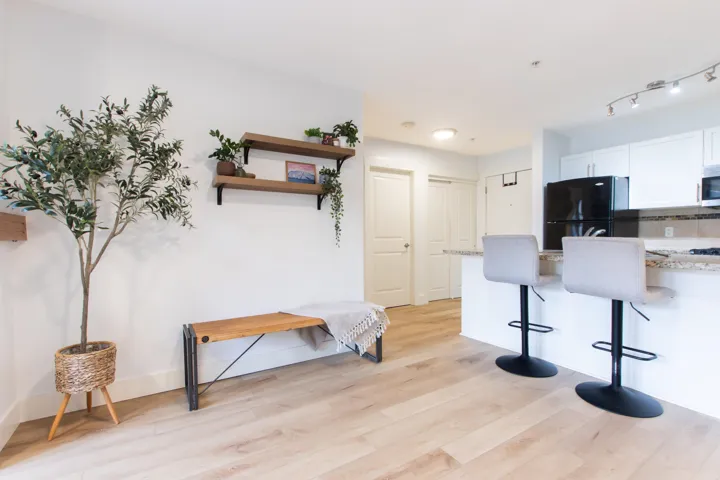 Kitchen with a breakfast bar area, tasteful backsplash, freestanding refrigerator, stainless steel microwave, and light wood-style flooring