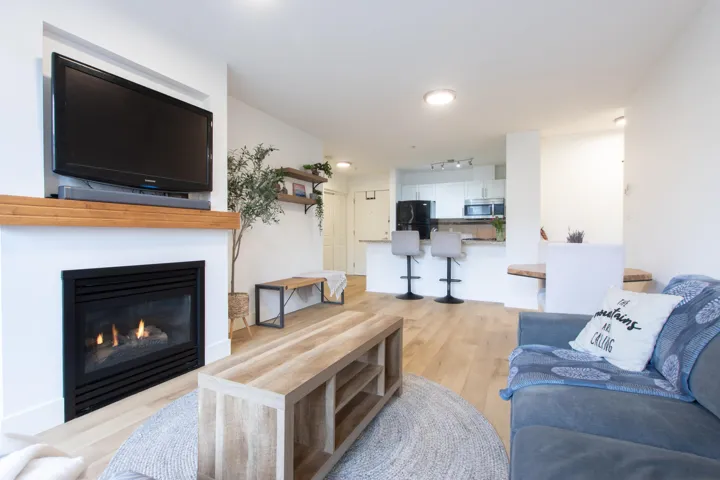 Living room with recessed lighting, light wood-style flooring, and a glass covered fireplace