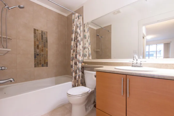 Bathroom with tile patterned flooring, toilet, shower / tub combo, and vanity
