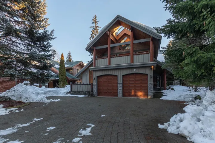 Chalet / cabin featuring stone siding, an attached garage, and decorative driveway