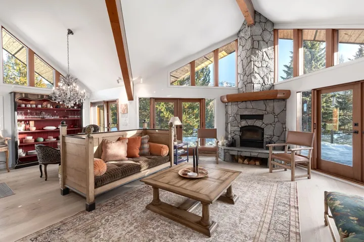 Living room with french doors, light wood-style flooring, a chandelier, a fireplace, and vaulted ceiling