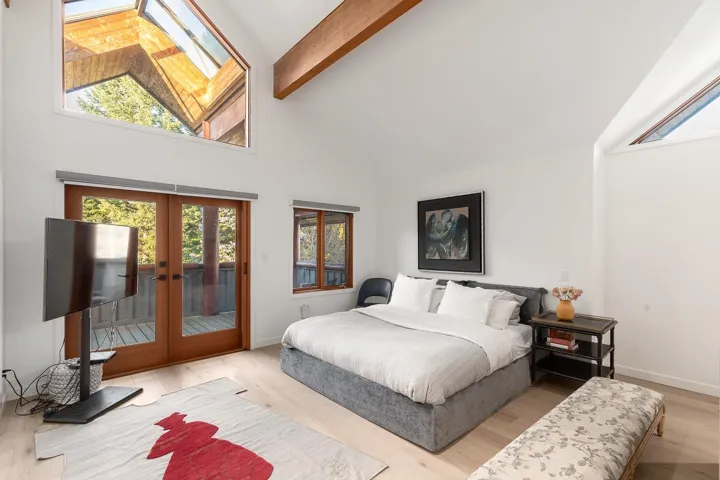 Bedroom featuring access to outside, wood finished floors, vaulted ceiling, french doors, and a skylight