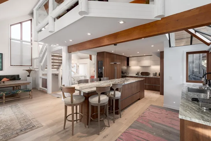 Kitchen with modern cabinets, light stone counters, a kitchen breakfast bar, light wood finished floors, and beam ceiling