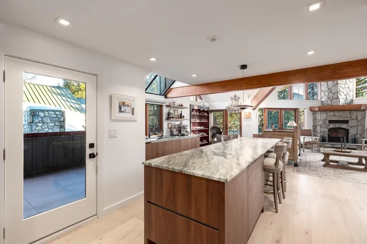 Kitchen with modern cabinets, wood finish cabinetry, a breakfast bar area, hanging light fixtures, and open floor plan