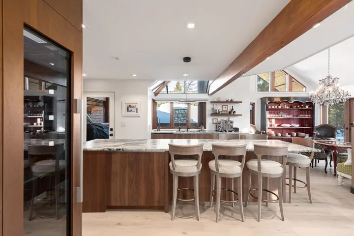 Kitchen featuring modern cabinets, light wood-style floors, light stone counters, suspended lighting, and lofted ceiling