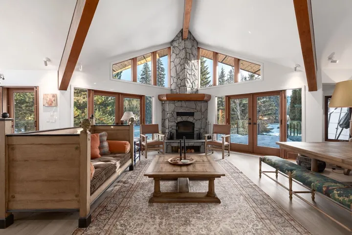 Living area featuring french doors, a stone fireplace, and light wood-style floors