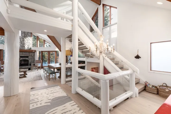 Stairway featuring a stone fireplace, a high ceiling, wood finished floors, hanging lights, and french doors