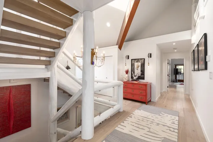 Hall featuring light wood-type flooring, vaulted ceiling with beams, and a chandelier