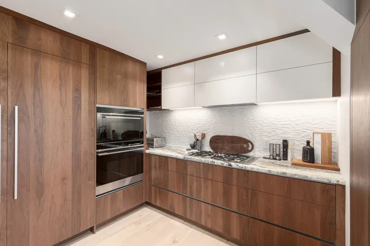 Dual tone kitchen featuring modern cabinets, open shelves, two tone color scheme, light stone counters, and multiple ovens