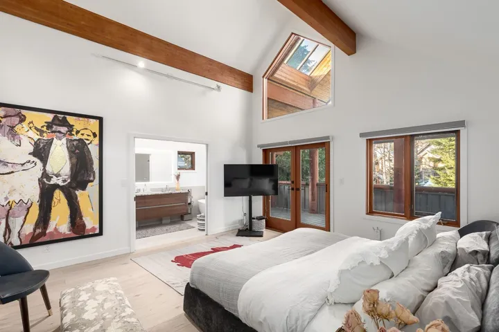 Bedroom featuring french doors, multiple windows, wood finished floors, access to outside, and vaulted ceiling