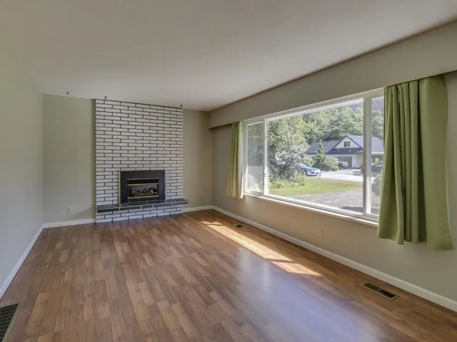 Unfurnished living room featuring wood finished floors and a brick fireplace