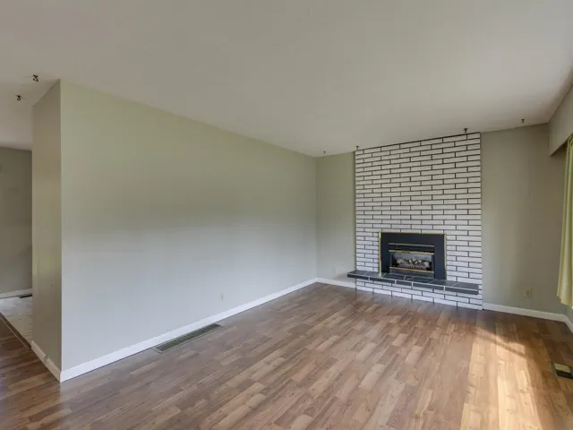 Unfurnished living room with wood finished floors and a brick fireplace