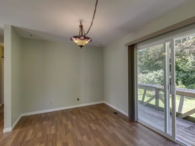 Unfurnished dining area with dark wood-style flooring and baseboards
