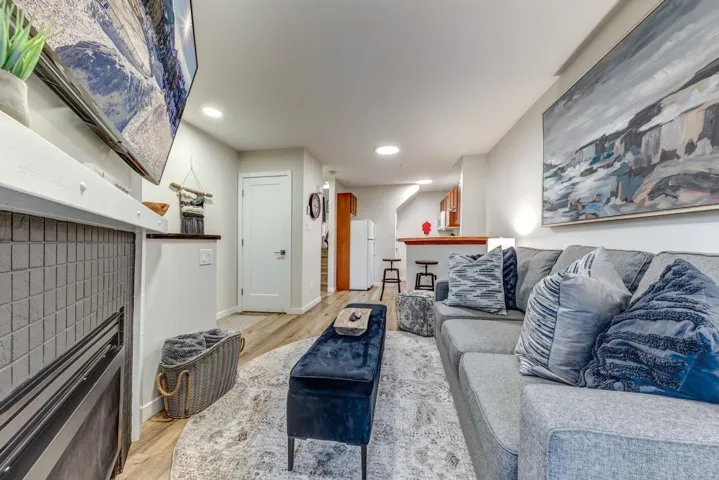 Living area featuring wood-finish flooring, a contemporary fireplace with tile surround, recessed lighting, and a breakfast bar with seating
