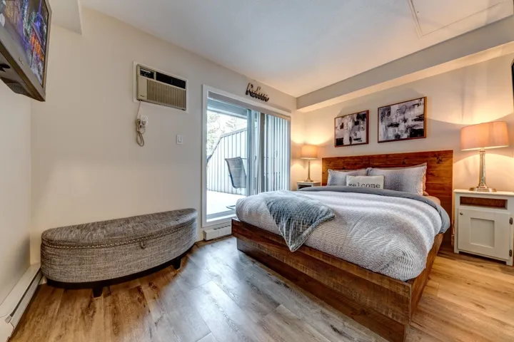 Bedroom featuring wood-finish flooring, a wood plank headboard, and a sliding glass door leading to a private patio