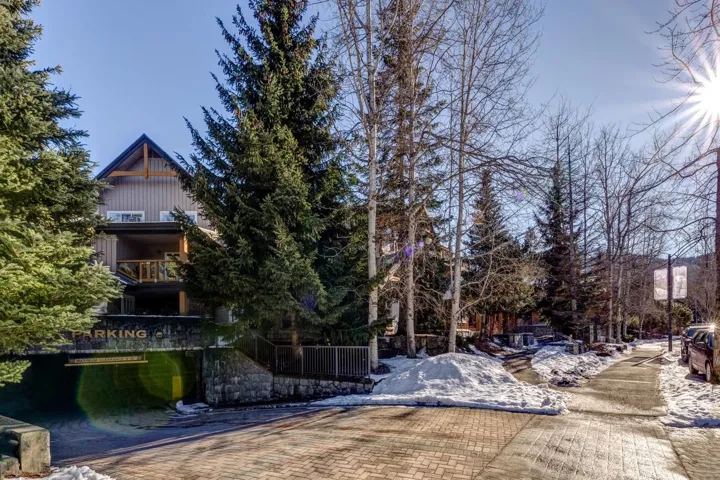 Mountain-style architecture featuring board-and-batten siding, a gable roofline with exposed timber framing, and a private balcony