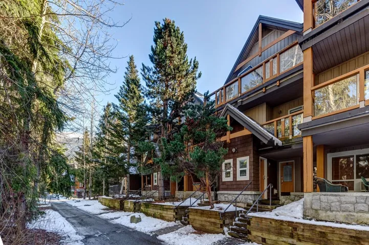 Multi-level property exterior featuring wood siding, stone accents, and a distinctive pitched roofline