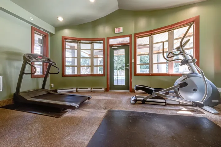 Recreational room featuring a door with glass panelling, multiple large windows with wood-finish trim, recessed ceiling lighting, and resilient flooring