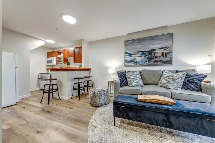 Open-concept living area featuring wood-finish flooring, recessed lighting, and a kitchen bar with seating