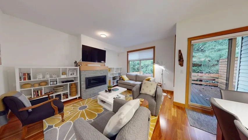 Living room with wood finished floors and a glass covered fireplace