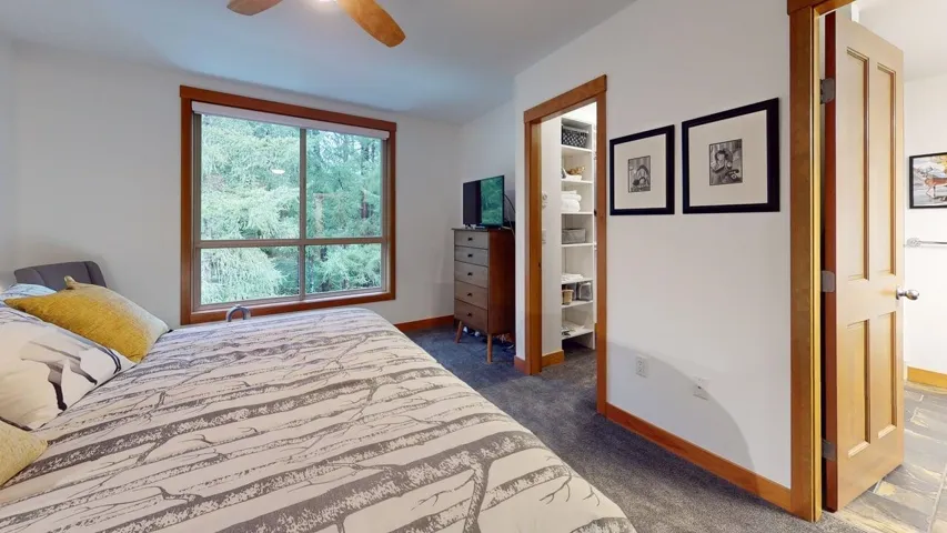 Bedroom featuring ceiling fan, dark colored carpet, and connected bathroom