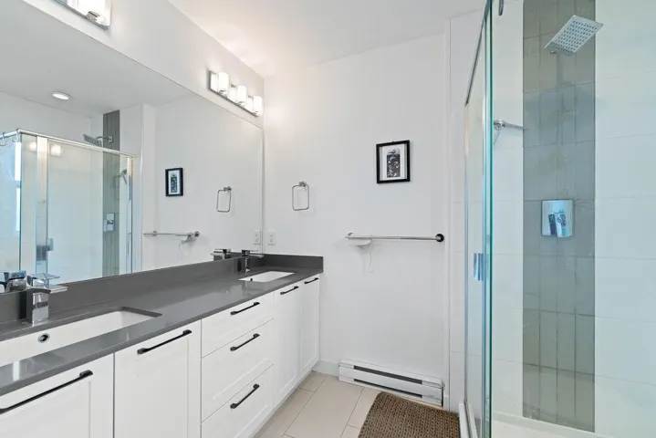 Bathroom featuring a sink, baseboard heating, a shower stall, and tile patterned floors