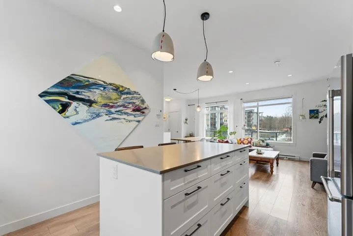 Kitchen with light wood finished floors, a center island, pendant lighting, high end refrigerator, and white cabinetry
