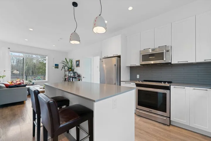 Kitchen featuring tasteful backsplash, white cabinetry, stainless steel appliances, and light wood-type flooring