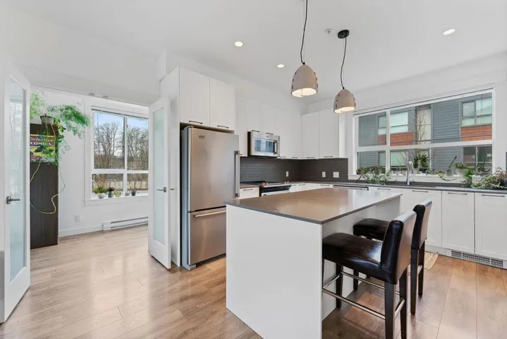 Kitchen with dark countertops, light wood-type flooring, a baseboard heating unit, and freestanding refrigerator