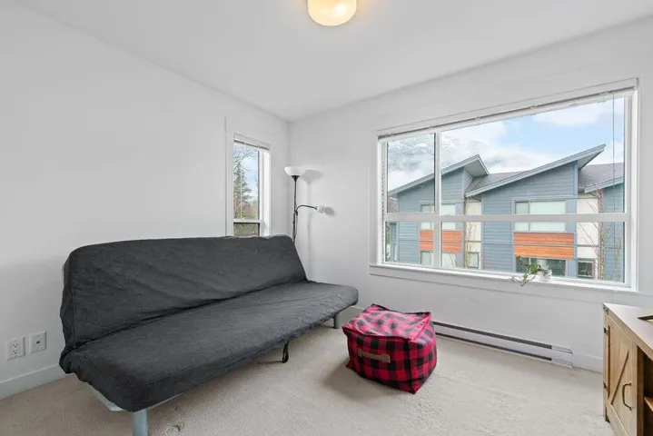 Sitting room featuring baseboards, light carpet, baseboard heating, and a healthy amount of sunlight
