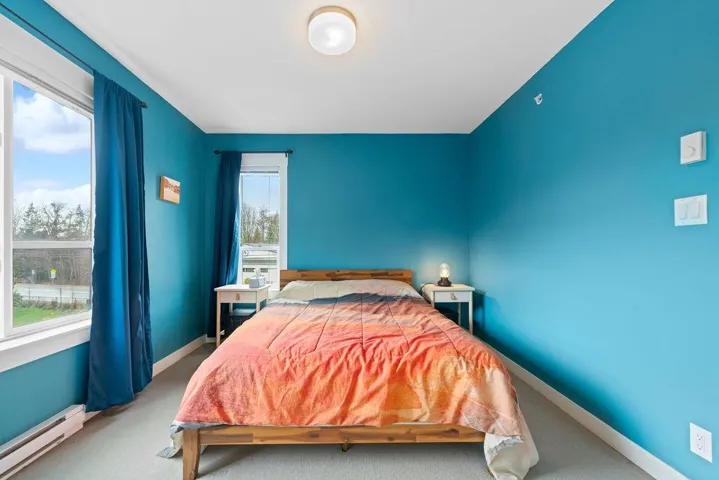 Carpeted bedroom with a baseboard heating unit and baseboards