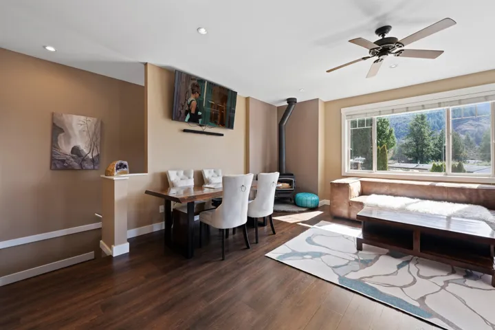 Dining space with a wood burning fireplace, wood floors, a ceiling fan, and recessed lighting.