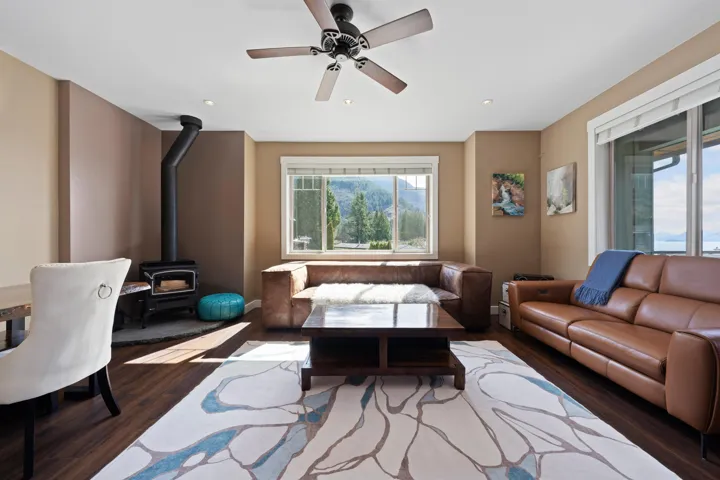 Living room featuring a wood stove, ceiling fan, dark wood-style flooring, and recessed lighting