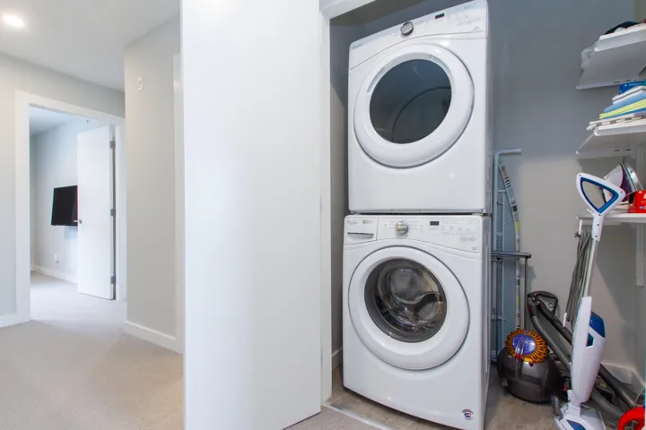 Laundry room featuring stacked washer / drying machine, baseboards, and carpet