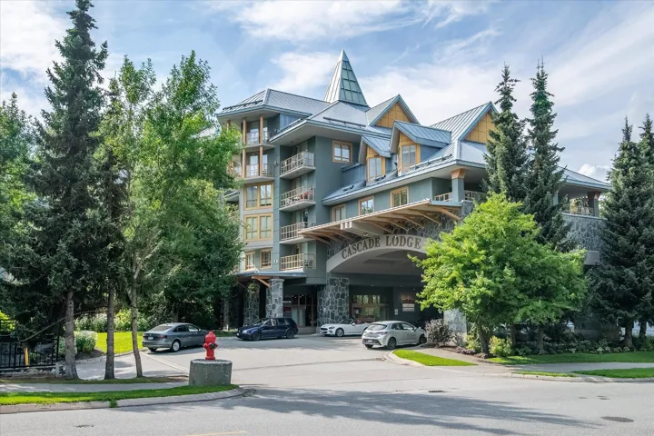 Multi-story building featuring a stone facade, prominent covered entrance, and multiple balconies