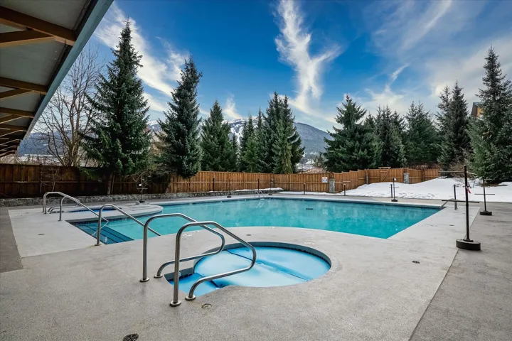 Outdoor swimming pool with an integrated spa, surrounded by a textured concrete deck