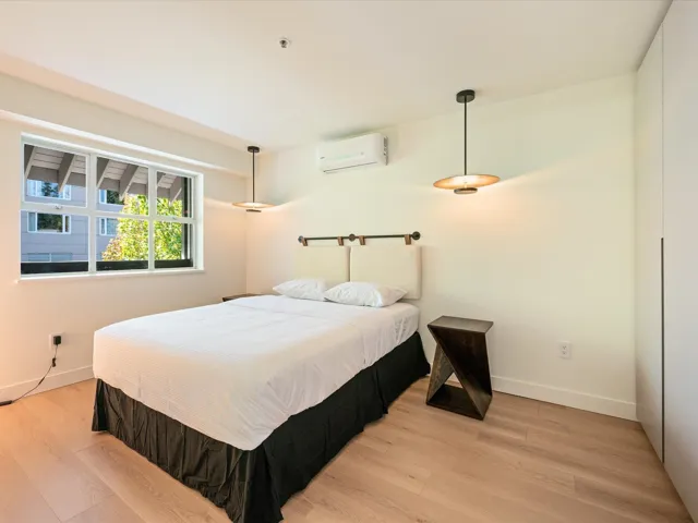 Bedroom with light wood-style flooring and a wall mounted air conditioner
